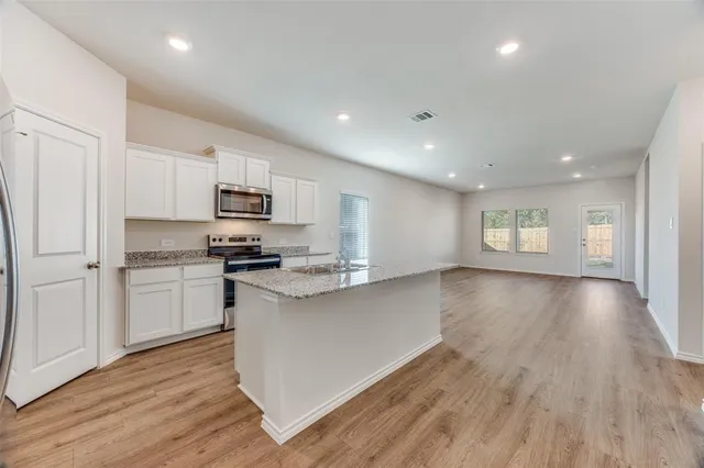 a kitchen with a sink wooden floor and stainless steel appliances