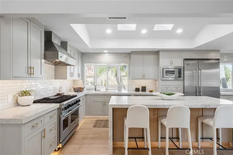 a kitchen with stainless steel appliances granite countertop a sink a stove a refrigerator cabinets and chairs