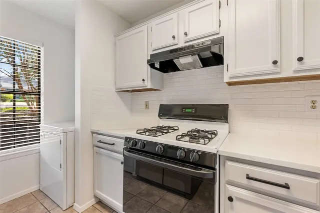 a kitchen with white cabinets and black appliances