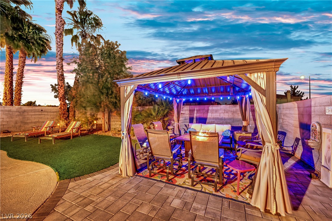 1724 Millstream Way Henderson, NV 89074 - Photo 54 of 60 An inviting outdoor living space features a covered patio with string lights, providing a perfect spot for evening relaxation.