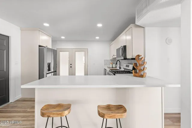 a kitchen with stainless steel appliances a white cabinets and a stove top oven