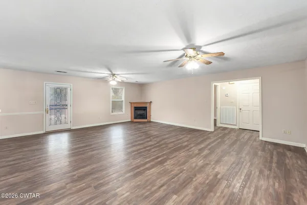 a view of an empty room with window and wooden floor