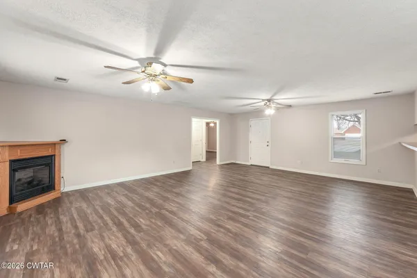 a view of an empty room with window and wooden floor
