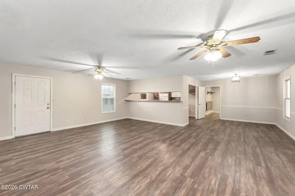 a view of a livingroom with a ceiling fan wooden floor and window