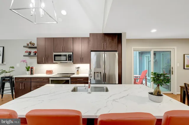 a kitchen with stainless steel appliances kitchen island granite countertop a refrigerator a stove a sink dishwasher and white cabinets with wooden floor