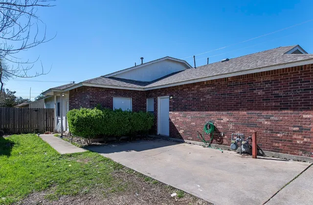 a view of a brick house with a small yard and plants