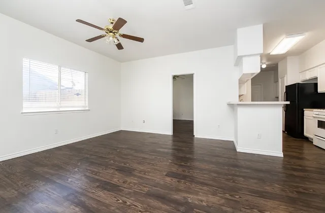 an empty room with wooden floor and a ceiling fan