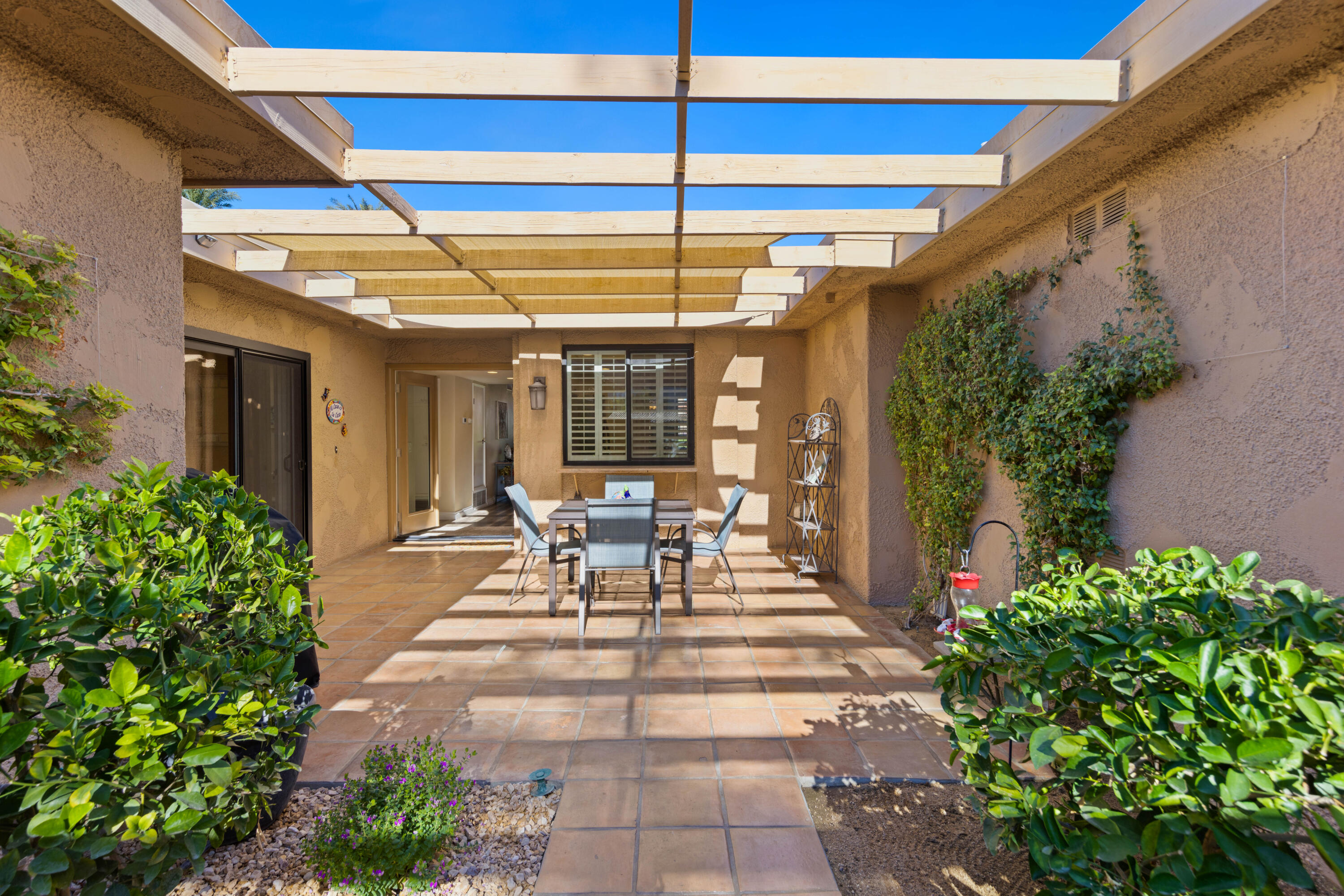 10 La Cerra Circle Rancho Mirage, CA 92270 - Photo 2 of 30 a view of a patio with table and chairs potted plants and floor to ceiling window