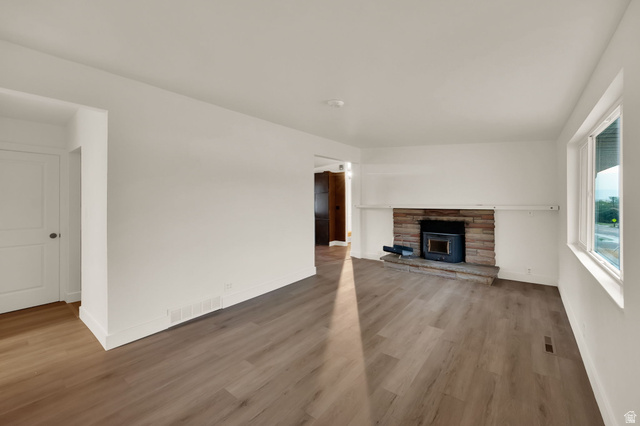 360 400 North Centerville, UT 84014 - Photo 11 of 30 Spacious room featuring wood-finish flooring, white baseboards, and a stone-clad fireplace with a dark insert