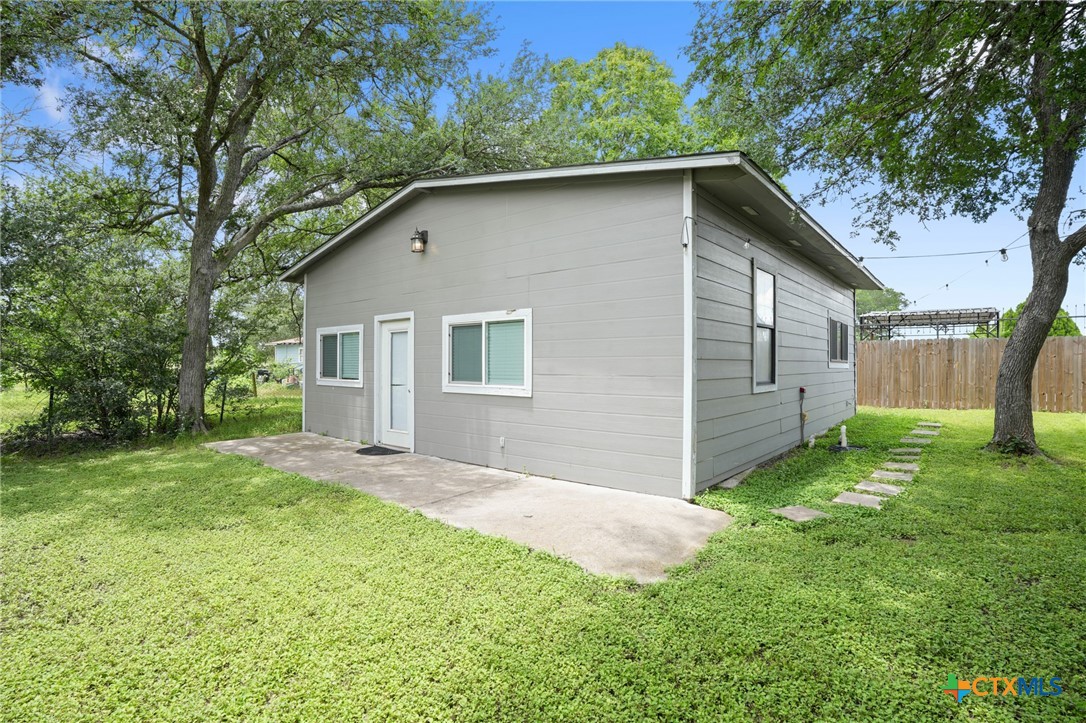 9725 Bock Road Buda, TX 78610 - Photo 27 of 37 A quaint rear structure with a patio awaits amidst a verdant lawn.