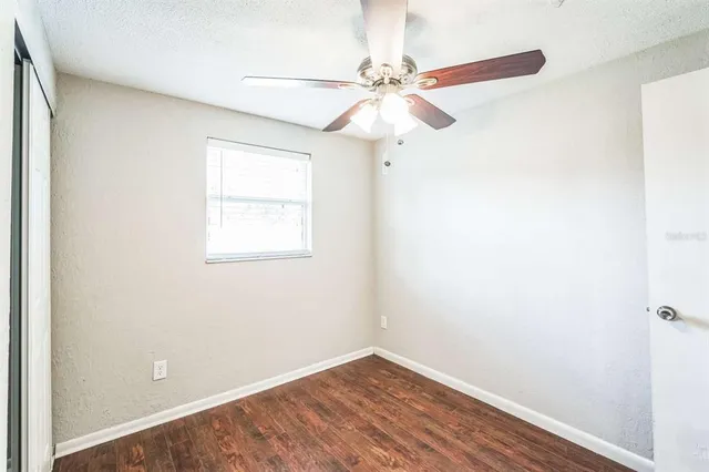 an empty room with wooden floor fan and windows