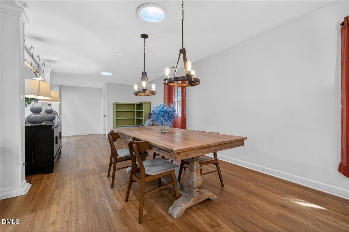 7303 Stony Hill Road Wake Forest, NC 27587 - Photo 9 of 31 a dining room with wooden floor a chandelier a wooden table and chairs