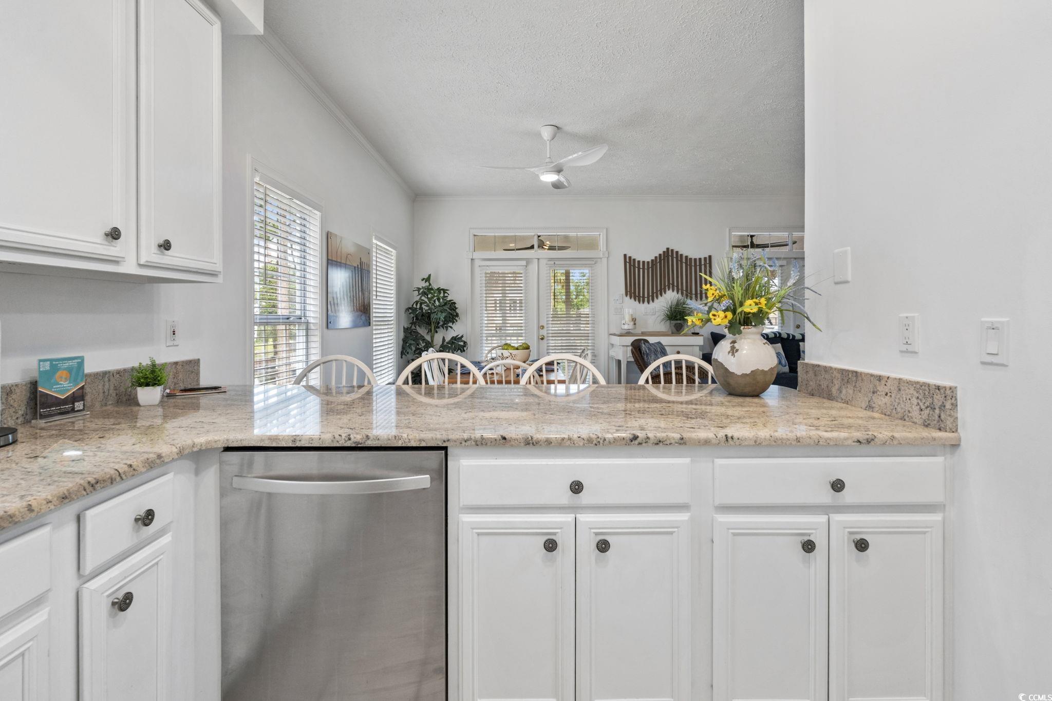327 A Lakeside Drive Surfside Beach, SC 29575 - Photo 12 of 40 Kitchen featuring stainless steel dishwasher, a peninsula, a textured ceiling, white cabinetry, and plenty of natural light