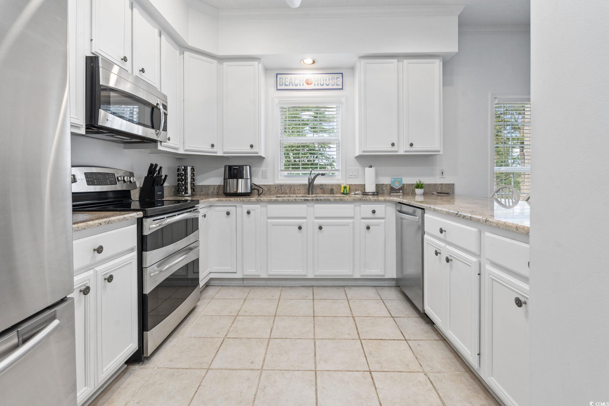 327 A Lakeside Drive Surfside Beach, SC 29575 - Photo 13 of 40 Kitchen featuring appliances with stainless steel finishes, a sink, ornamental molding, white cabinetry, and light tile patterned floors