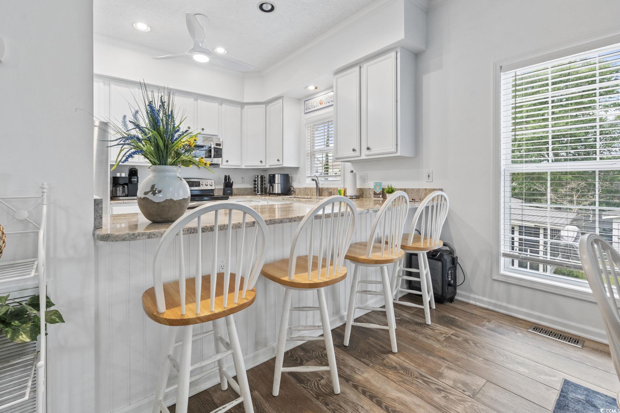 327 A Lakeside Drive Surfside Beach, SC 29575 - Photo 14 of 40 Kitchen with appliances with stainless steel finishes, light stone countertops, wood finished floors, white cabinets, and recessed lighting