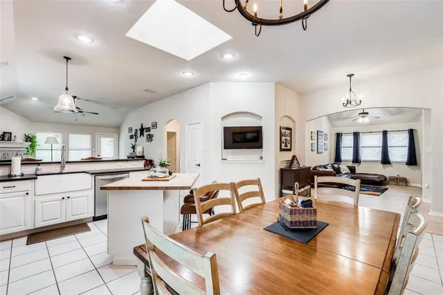 a kitchen with stainless steel appliances granite countertop a stove white cabinets a dining table and chairs with white cabinets