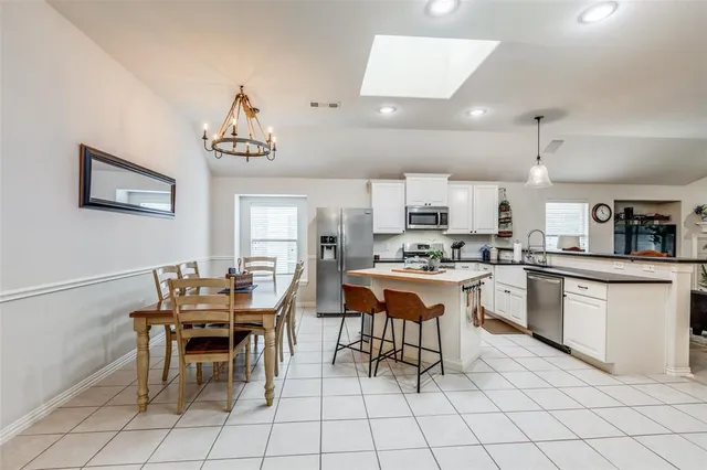 a kitchen with a dining table chairs and white cabinets