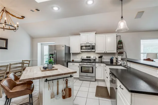 a kitchen with stainless steel appliances granite countertop a sink a stove a refrigerator cabinets and chairs
