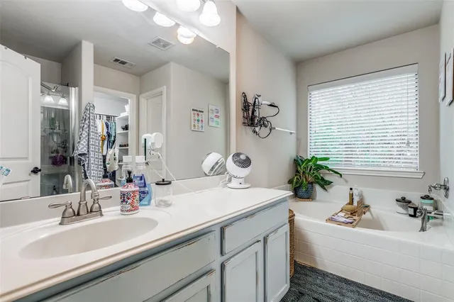 a bathroom with a tub a sink and mirror