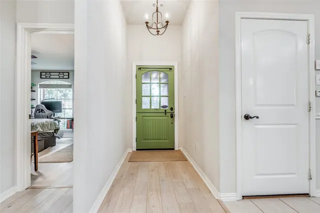 a view of a hallway with wooden floor and a kitchen