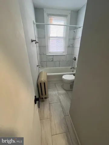 a bathroom with a granite countertop toilet a sink and a window