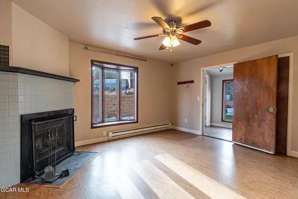 an empty room with windows fireplace and a ceiling fan