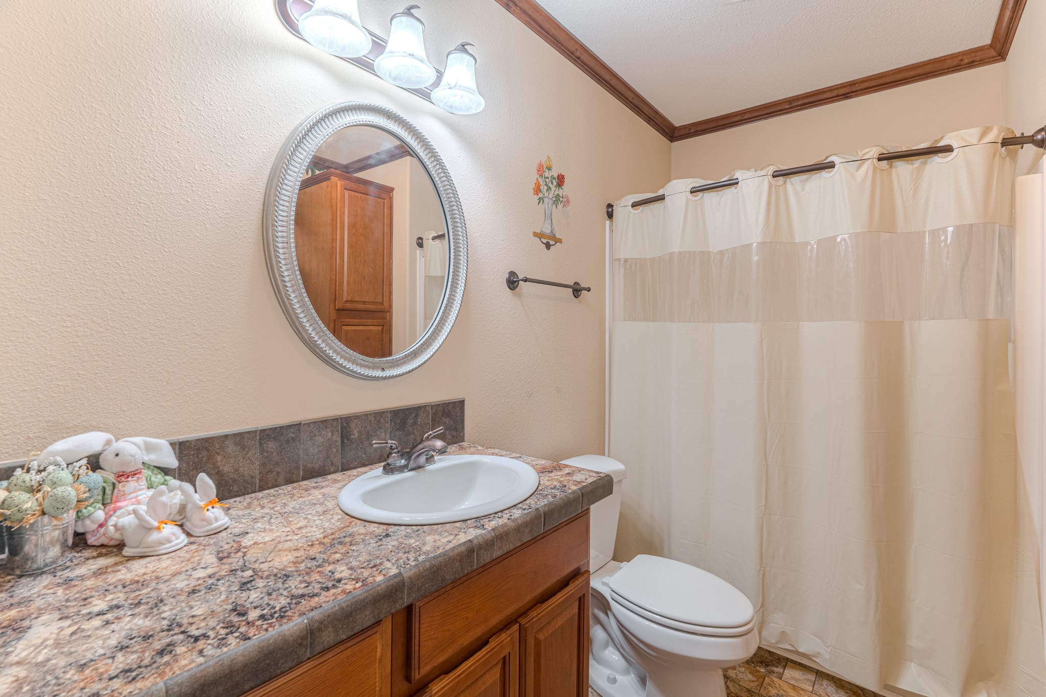 115 Canadian Drive Trinity, TX 75862 - Photo 20 of 42 Second bathroom features an elegant oval mirror, warm wood cabinetry, and inviting shower space, perfect for enhancing your home's comfort.