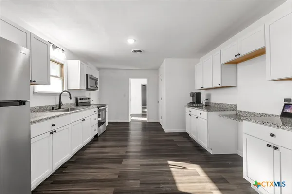 a large kitchen with granite countertop lots of counter top space sink and cabinets