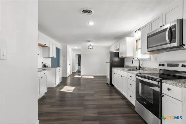 a large kitchen with stainless steel appliances granite countertop a lot of counter space and wooden floor
