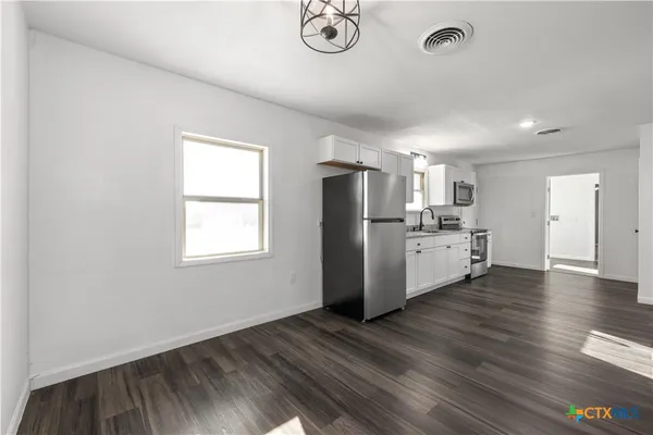 a view of a kitchen with wooden floor and electronic appliances