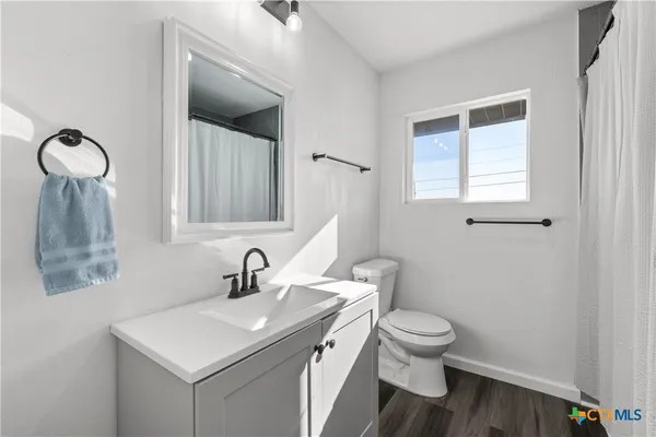 a bathroom with a toilet a sink a mirror and a window