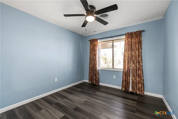 a view of empty room with wooden floor and fan
