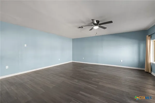 a view of an empty room with window and wooden floor