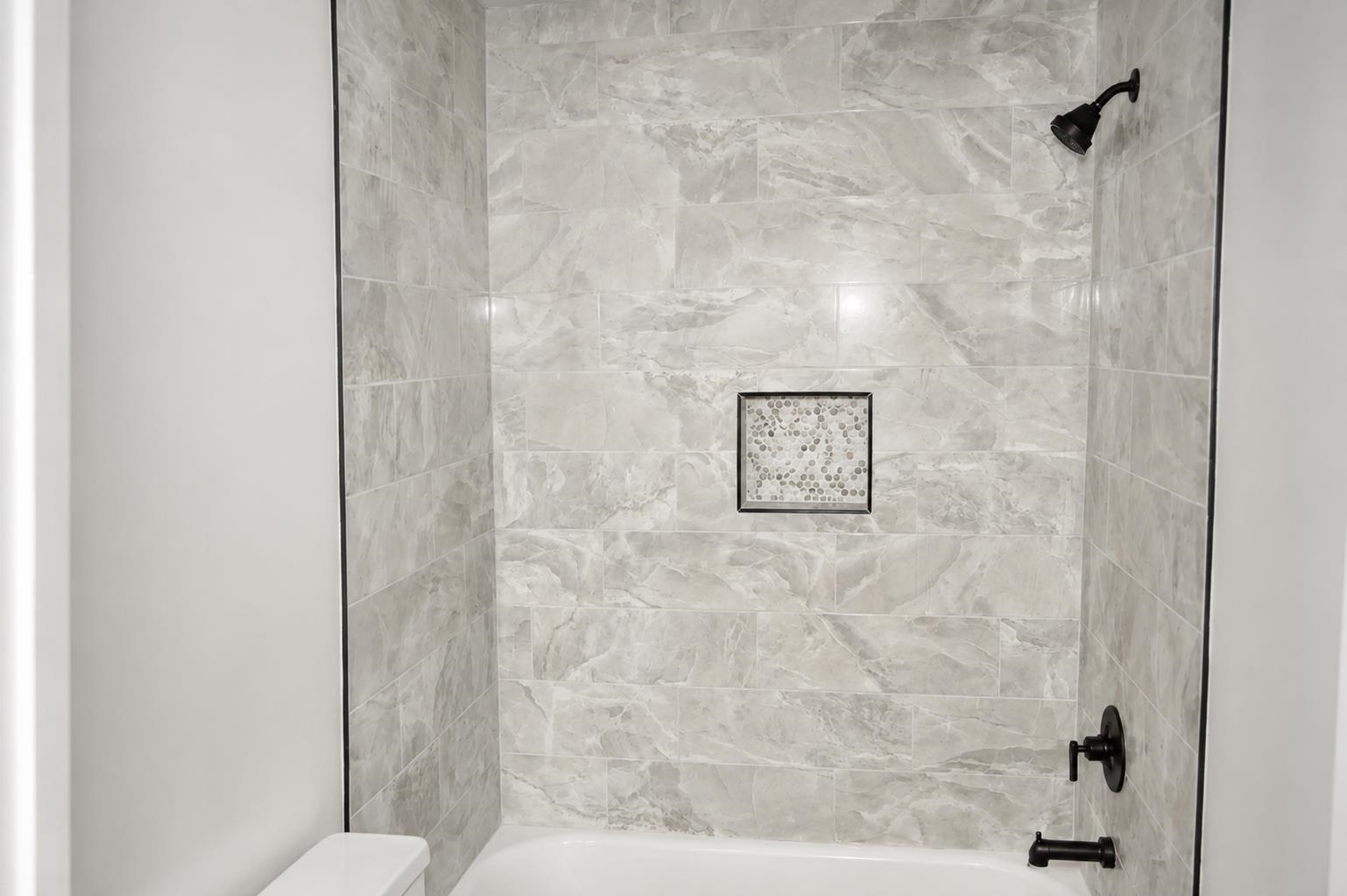 1687 East Alcy Road Memphis, TN 38114 - Photo 5 of 7 Tub and shower combination featuring large format grey veined tile, matte black showerhead and fixtures, and a recessed tile niche with mosaic detailing