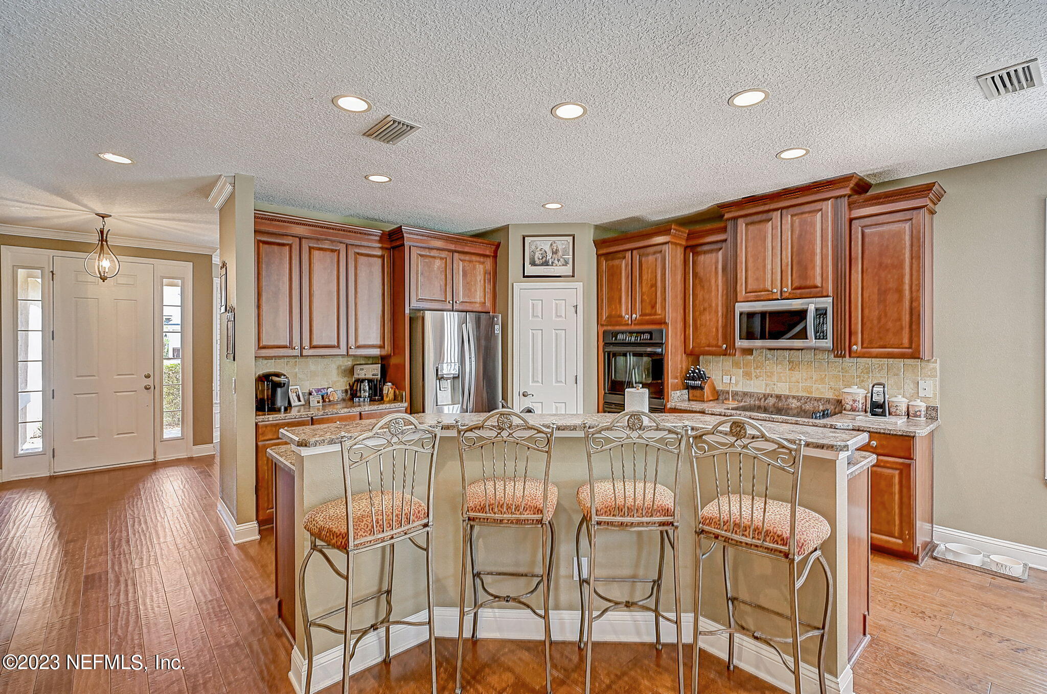1828 Rear Admiral Lane St. Johns, FL 32259 - Photo 18 of 48 a kitchen with stainless steel appliances granite countertop a stove top oven a refrigerator a sink and a dining table with wooden floor