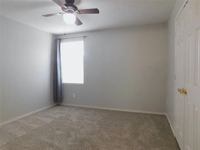 an empty room with a window and a fan