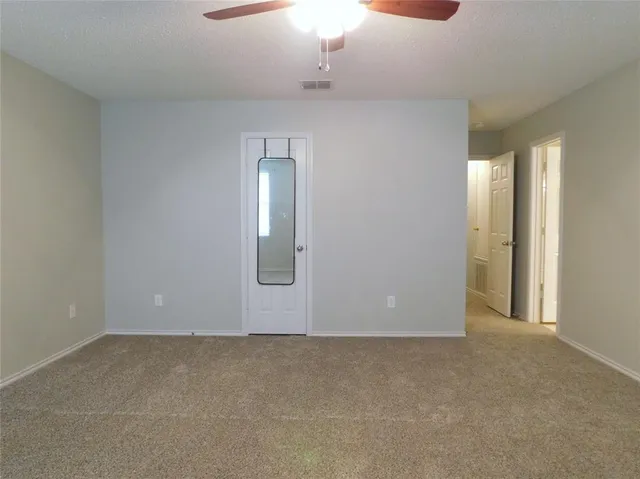 an empty room with a window and a fan
