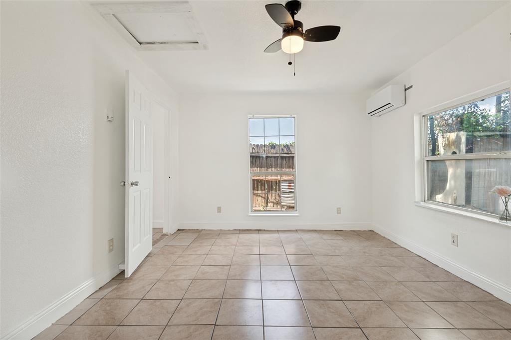 403 North Britain Road, Unit 407B Irving, TX 75061 - Photo 6 of 11 Bright room featuring neutral tile flooring, white walls, two windows, and a ceiling fan with integrated lighting