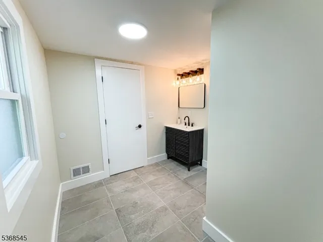 a view of an empty room and bathroom with mirror