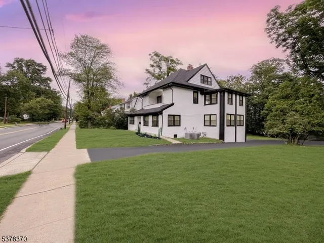 a view of a white house with a big yard and large trees