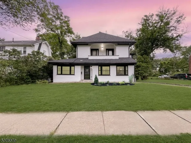 a view of a yard in front of a brick house with a large tree