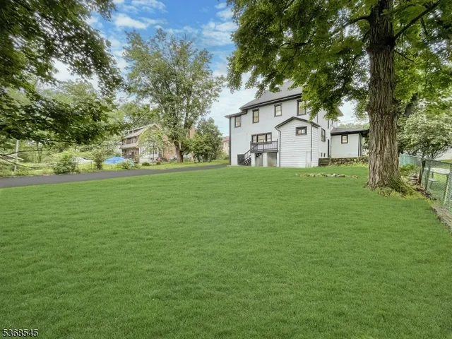a view of a house with a big yard and large trees