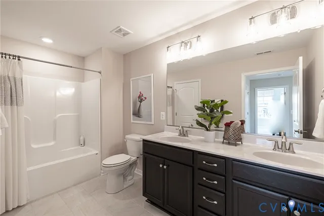 a spacious bathroom with a double vanity sink toilet mirror and bathtub