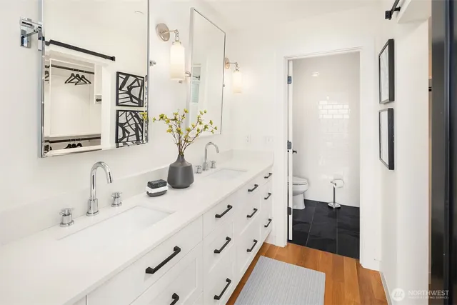 a bathroom with double vanity sink a mirror a glass door a shower and vanity