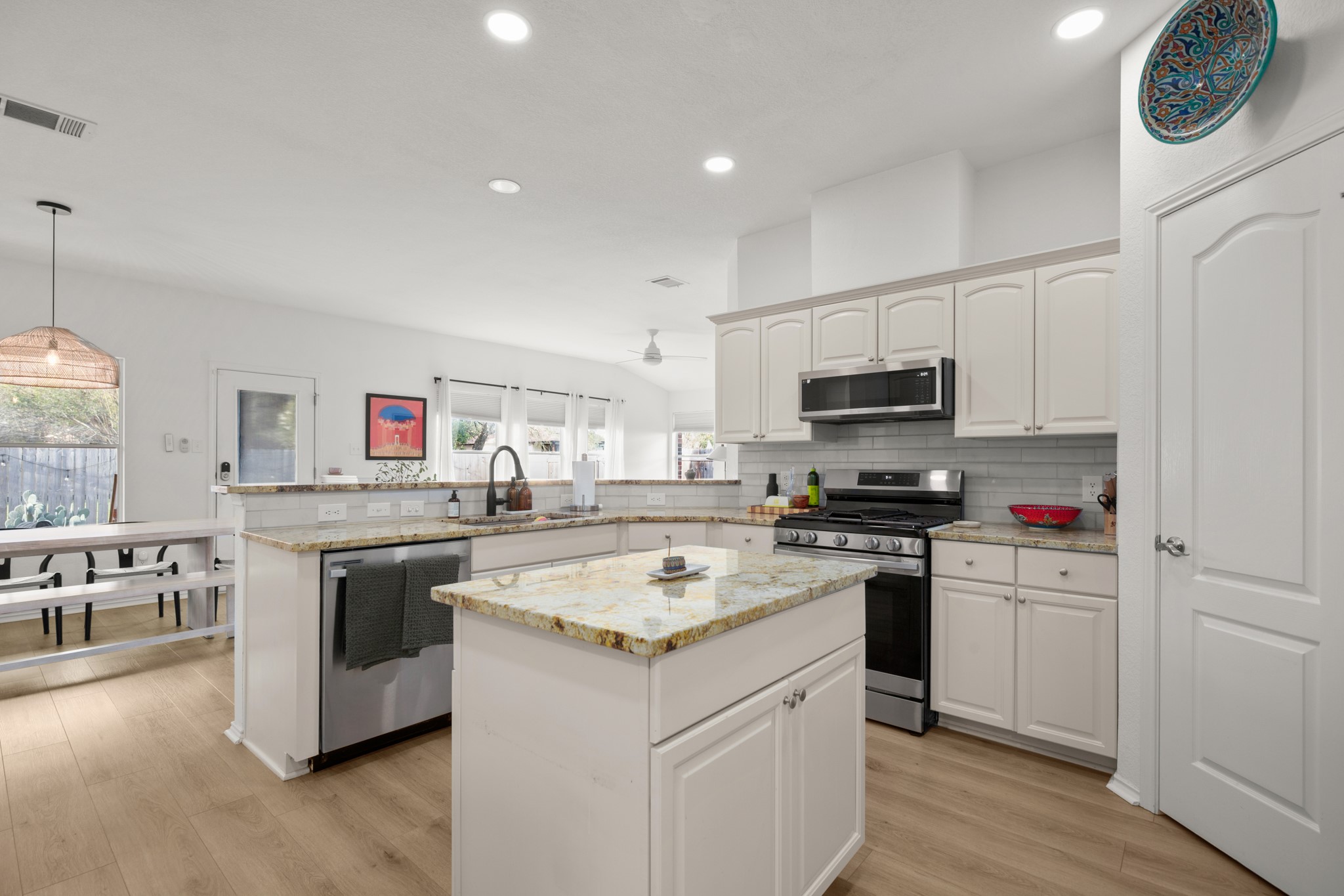 4523 Ramies Run Austin, TX 78749 - Photo 13 of 30 Kitchen with stainless steel appliances, a peninsula, light wood-type flooring, a center island, and white cabinets