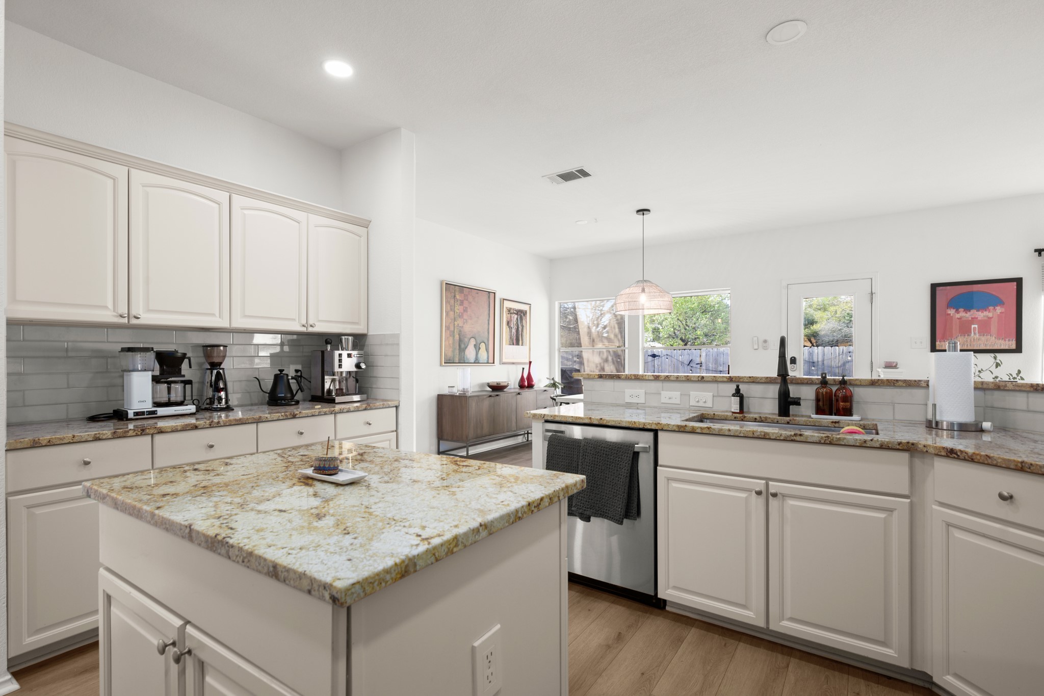 4523 Ramies Run Austin, TX 78749 - Photo 26 of 30 Kitchen featuring white cabinetry, light stone countertops, light wood-style floors, a kitchen island, and dishwasher