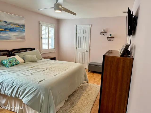 a bedroom with a bed and flat tv screen on the dresser