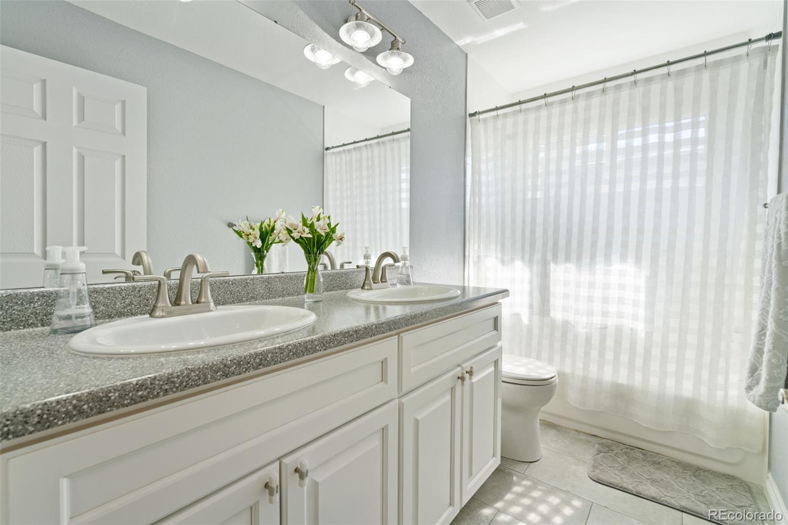 2667 West Bitterroot Place Highlands Ranch, CO 80129 - Photo 32 of 40 a bathroom with a granite countertop sink a toilet and a mirror