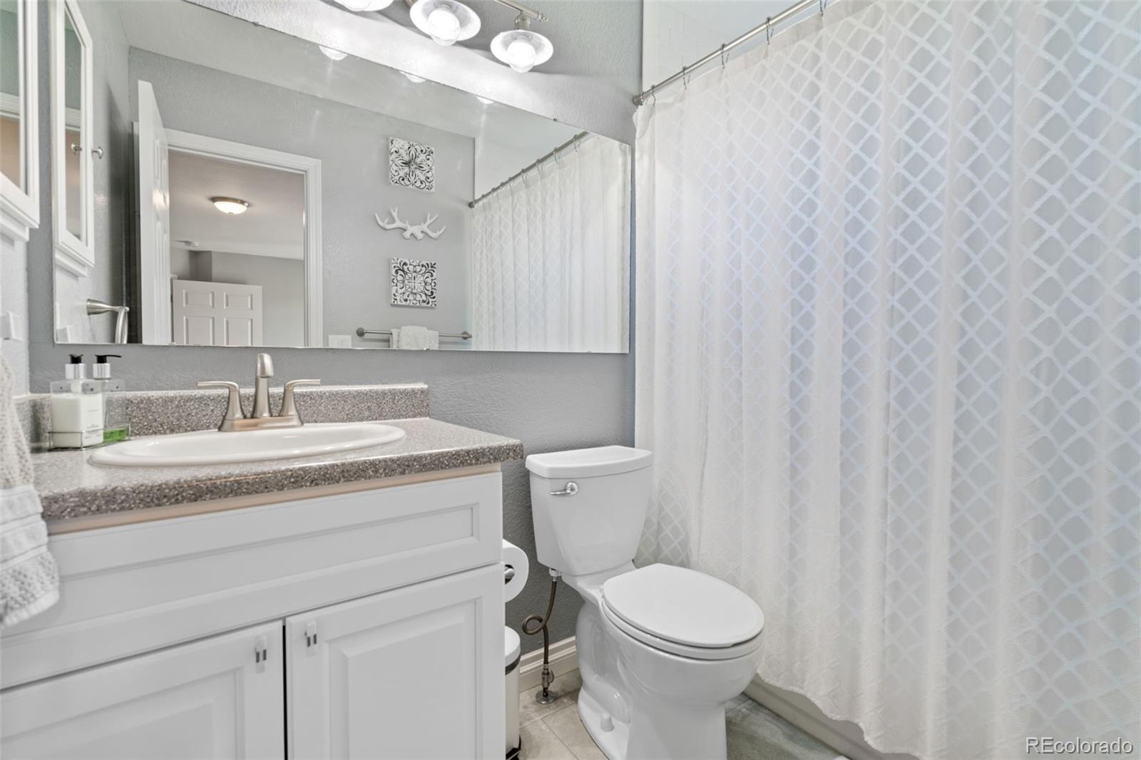 2667 West Bitterroot Place Highlands Ranch, CO 80129 - Photo 33 of 40 a bathroom with a granite countertop sink toilet and a mirror