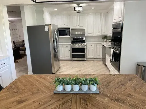 a kitchen with stainless steel appliances kitchen island granite countertop a refrigerator a stove and a sink with wooden floor